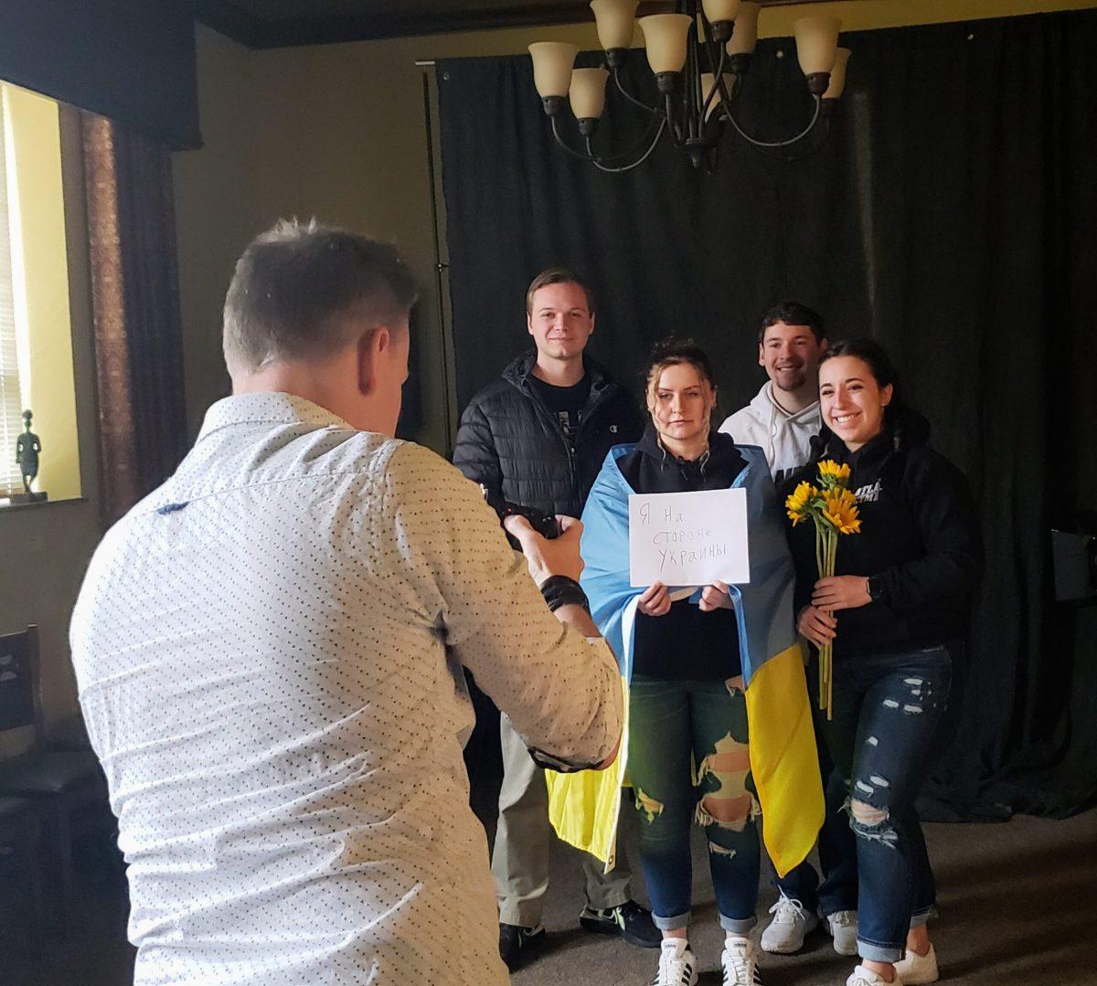 Students pose for a photo, with a sign reading "I stand with Ukraine" in Russian.