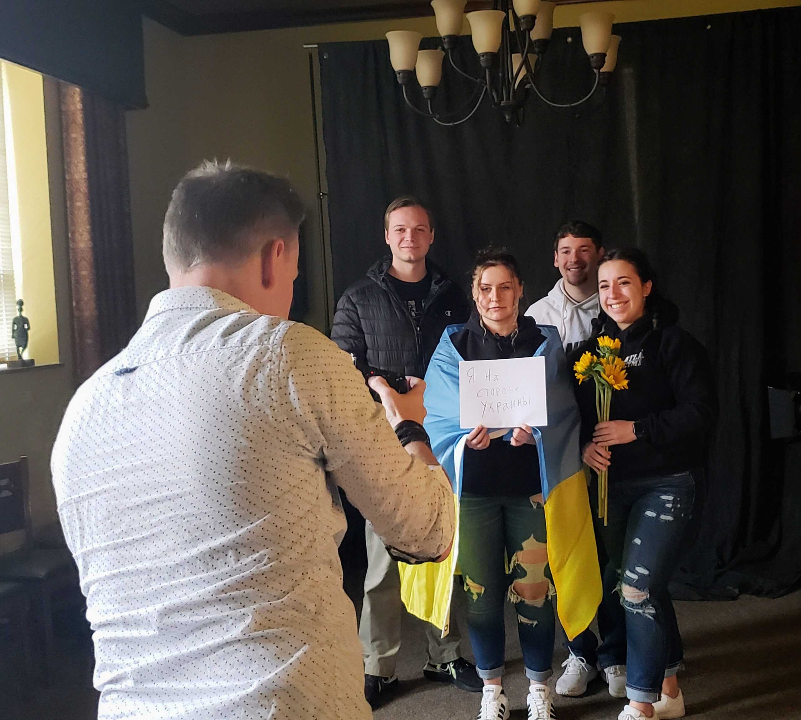 Students pose for a photo, with a sign reading "I stand with Ukraine" in Russian.